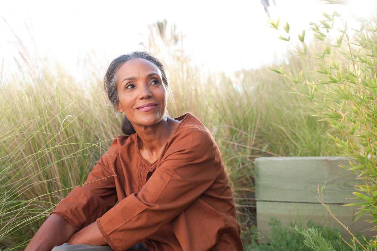 Serene woman sitting in sunny field Serene woman sitting in sunny field