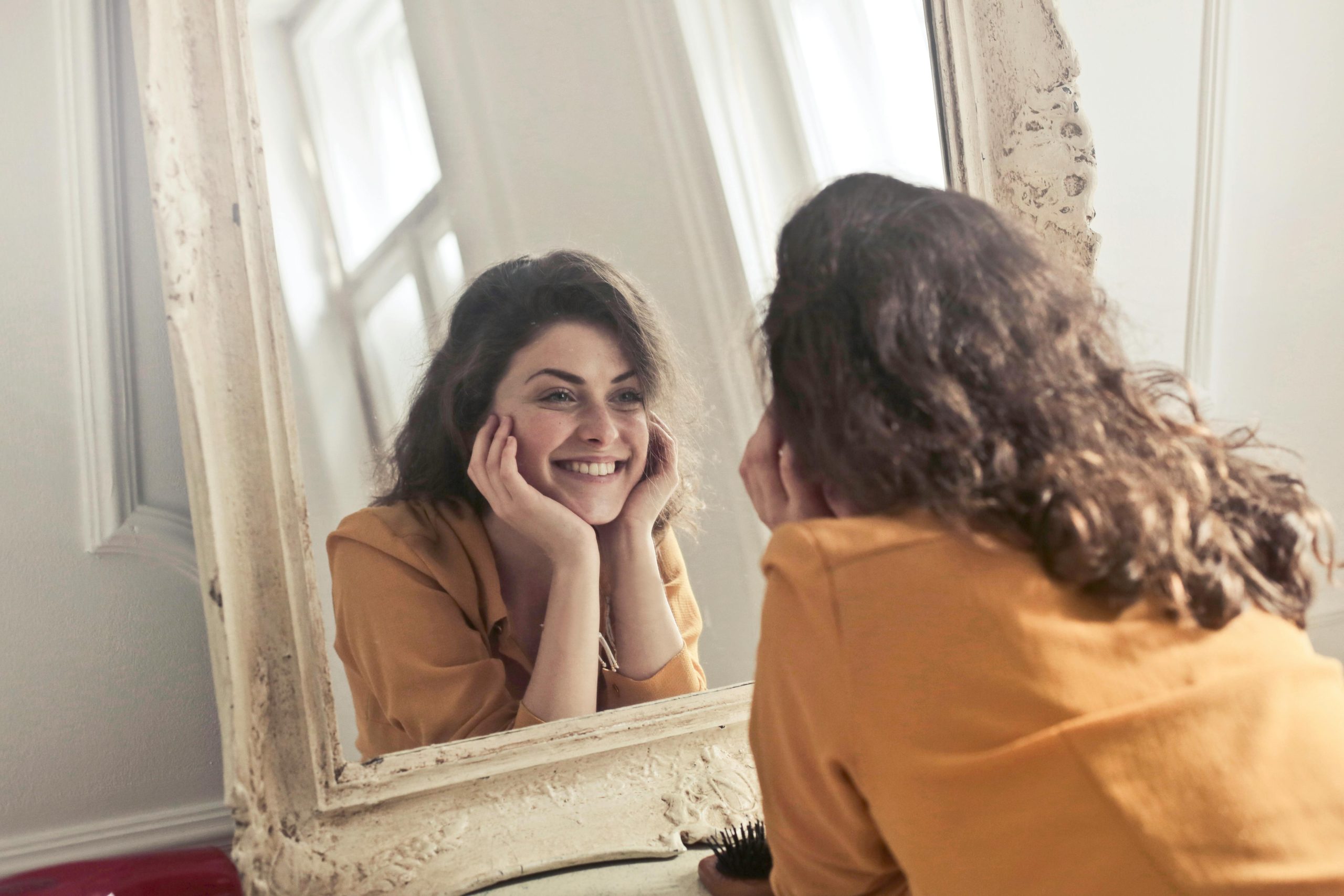 "person looking at their brows in the mirror"