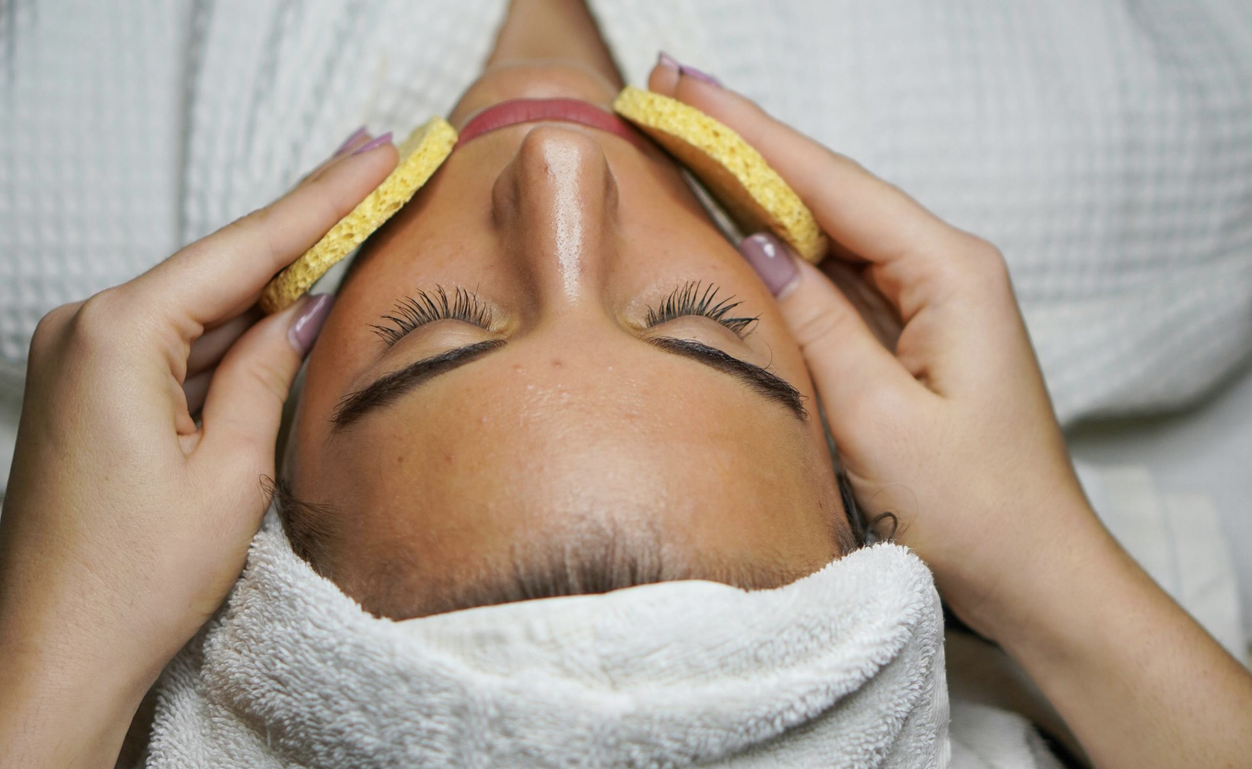 Facial: Winnipeg spa treatments Skin Specialist Winnipeg - A person getting a facial cleanse with sponges during a spa treatment in Winnipeg
