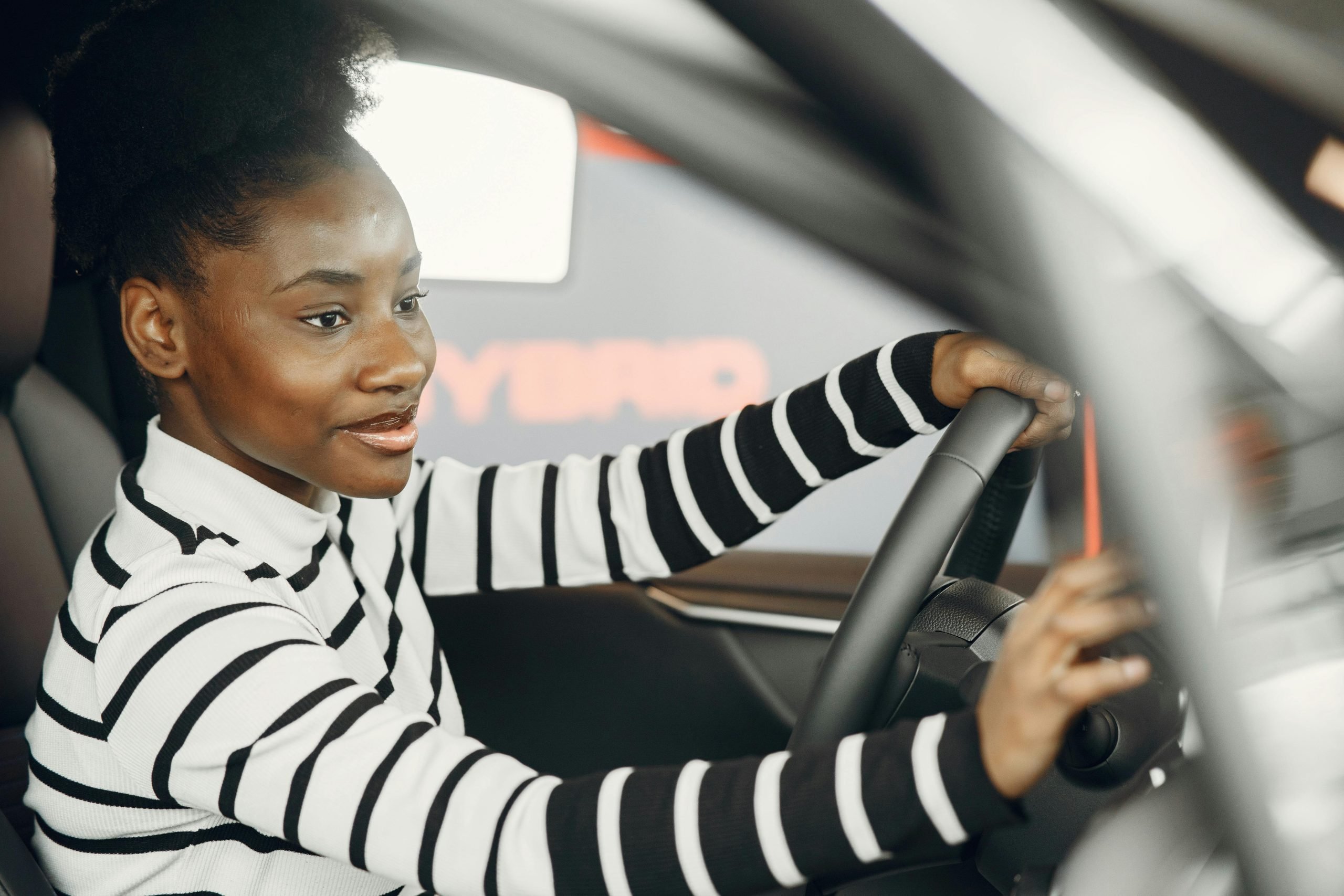 A commuter in her car who is smiling knowing she is going to get her beauty services done and that her skin is protected from UVA rays due to SPF