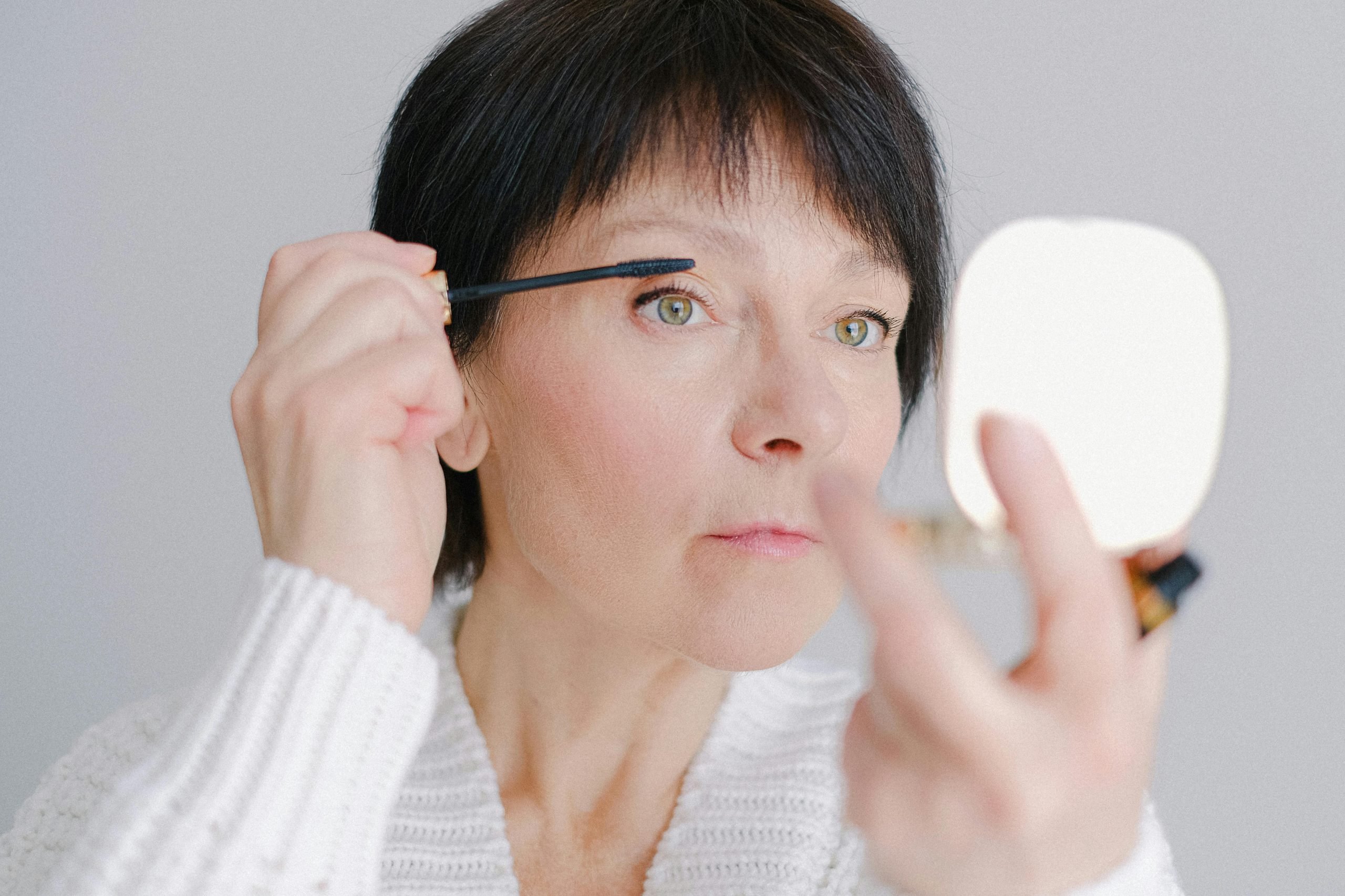 A future lash extension headingley client who is thinking of how tired she is of applying mascara every morning as she does so in the mirror