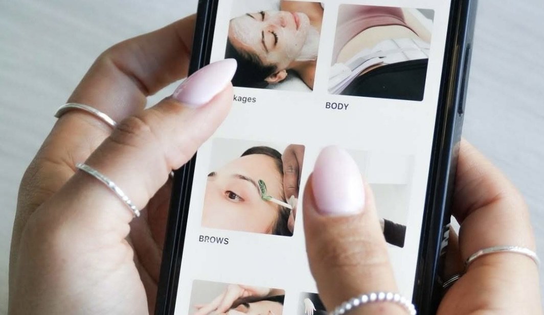 a hand holding a phone showing the Total Wrapture Medi Spa app and booking after getting a monthly plan