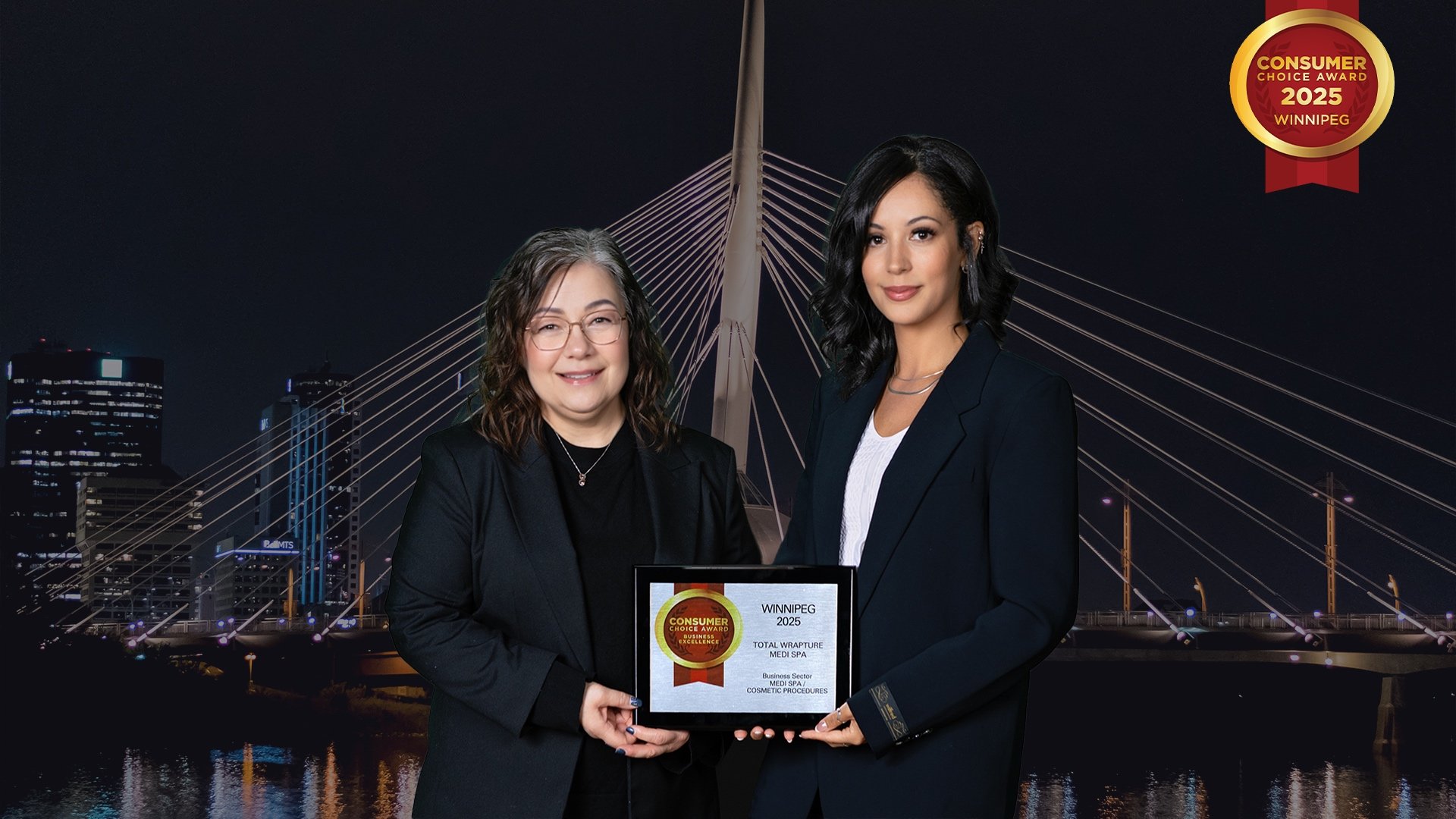 Two women dressed in black holding up an award against a backdrop of a Winnipeg landmark. Mel and Nathalie at the CCA Consumer Choice Awards 2025 for Best Medi Spa in Winnipeg.