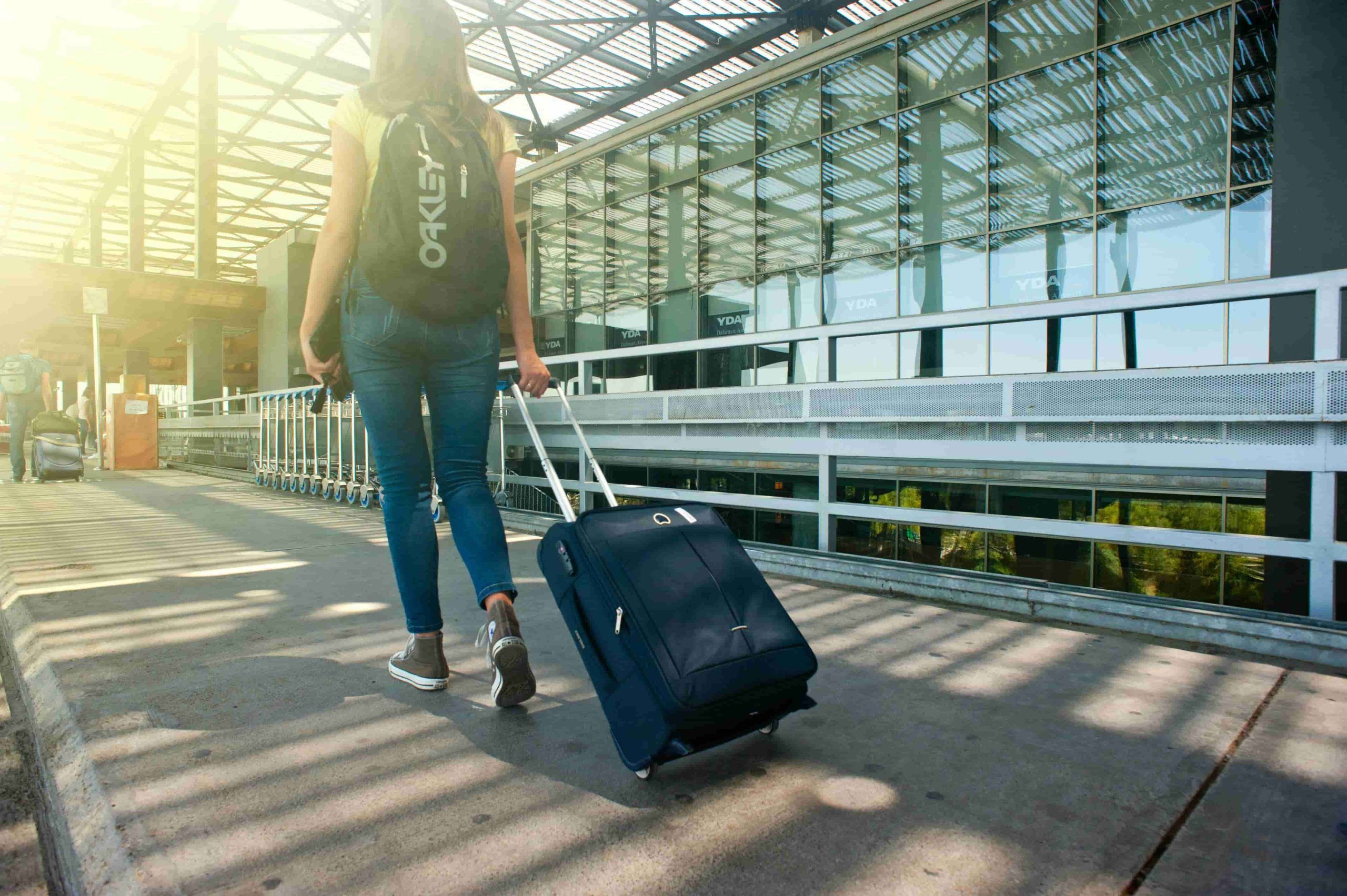 Traveller walking with luggage outside an airport, a reminder that Skincare Tips for Travelling help protect skin from stress, sun, and long journeys.