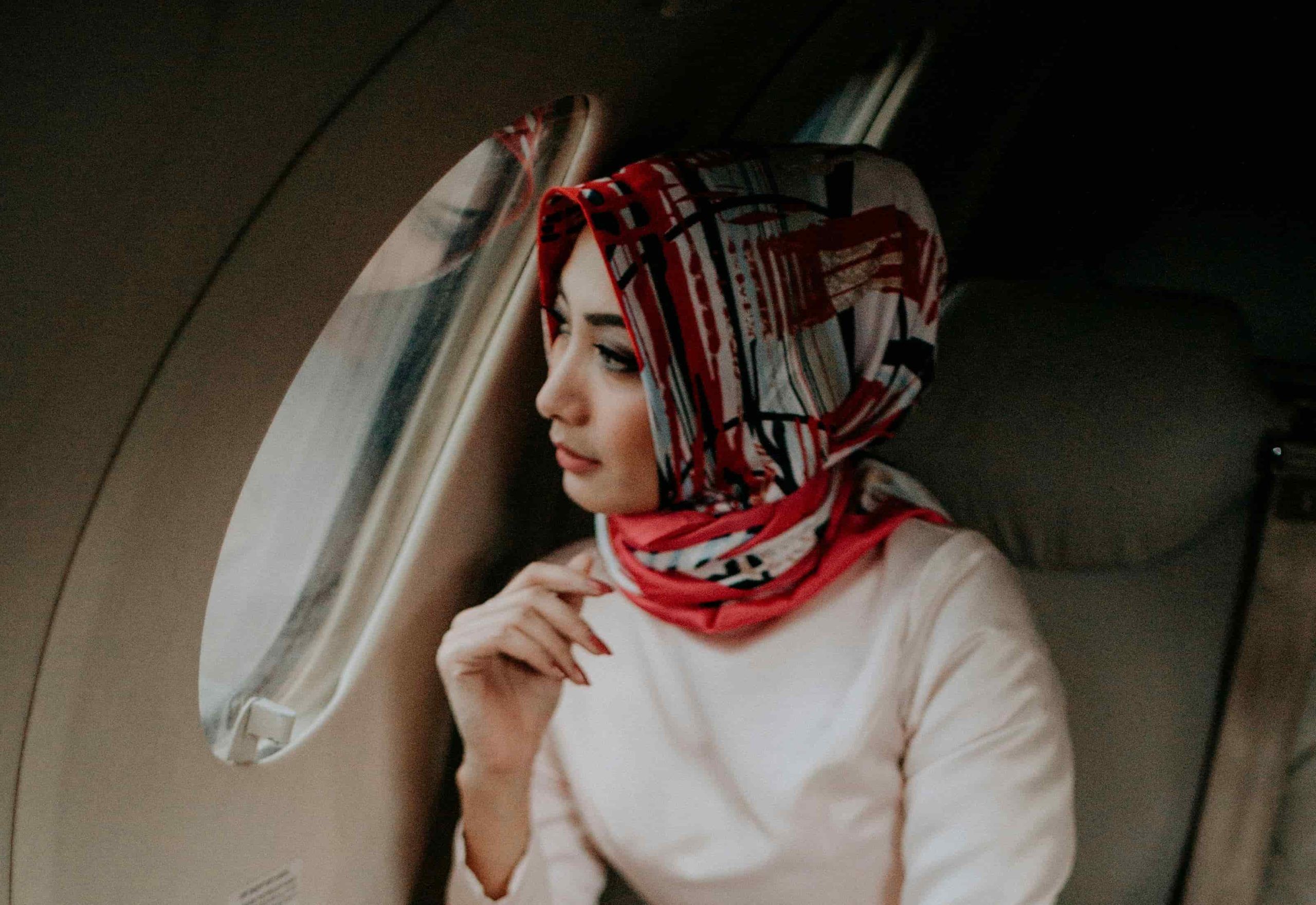  Woman gazing out airplane window, a reminder that Skincare Tips for Travelling help fight dryness and keep skin radiant on long flights.
